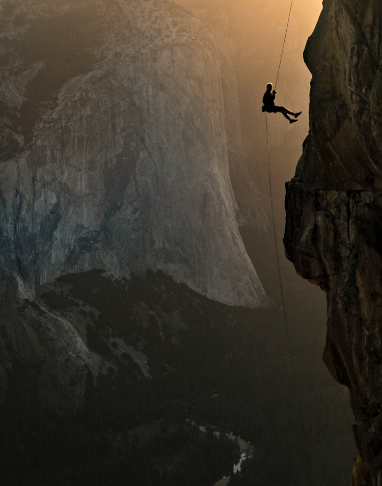 Person rappelling down large mountainside